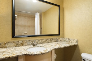 A bathroom with a marble sink, a large mirror, and a shower area.