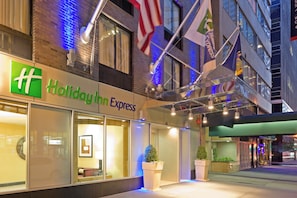 Un h ôtel Holiday Inn Express avec une façade en briques, de grandes fenêtres et une enseigne portant le nom de l’hôtel.