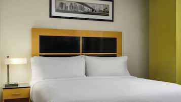 A hotel room with a bed, a nightstand, a lamp, and a framed cityscape picture on the wall.