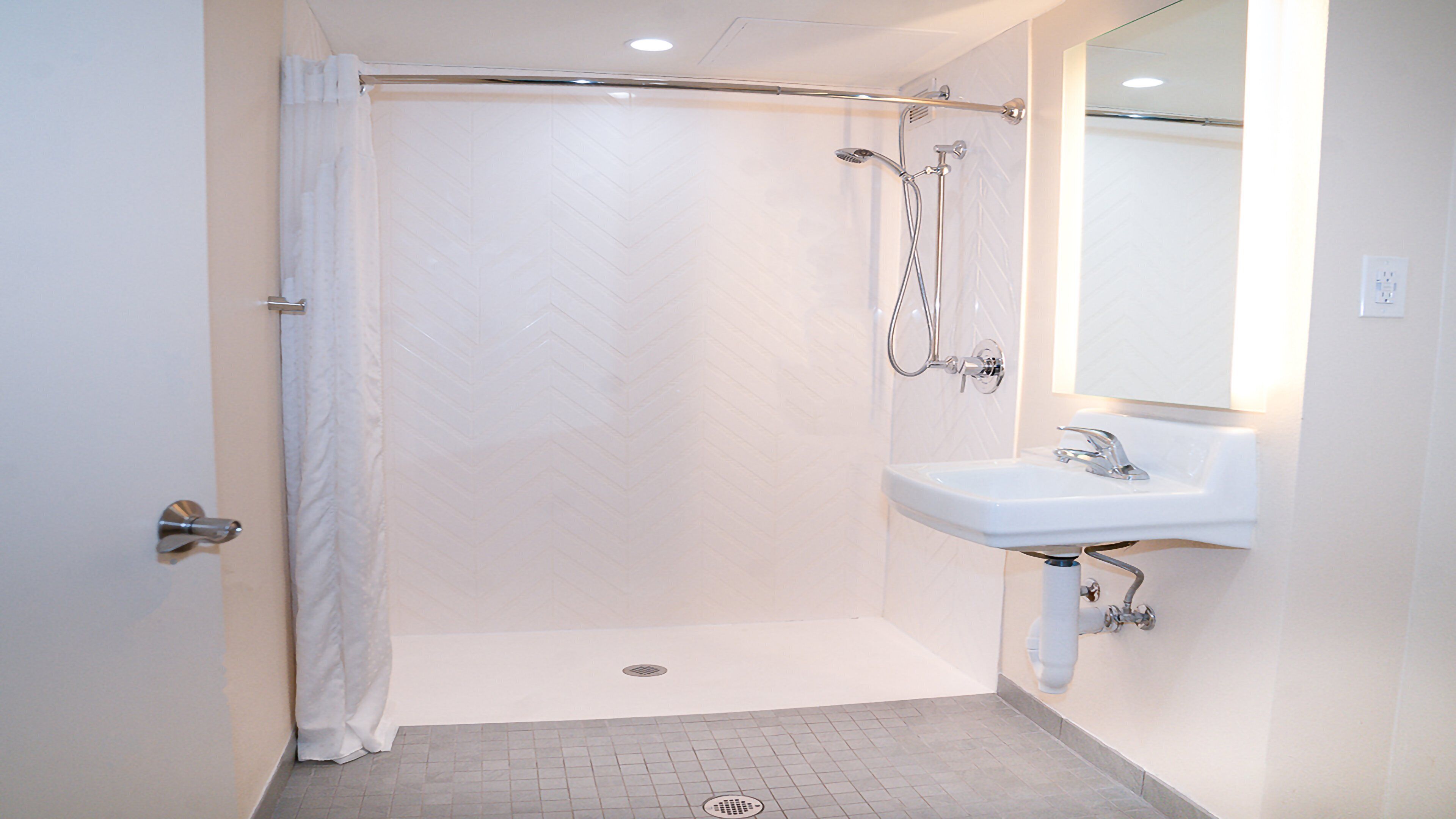 A modern bathroom with a shower, a sink, and a mirror.