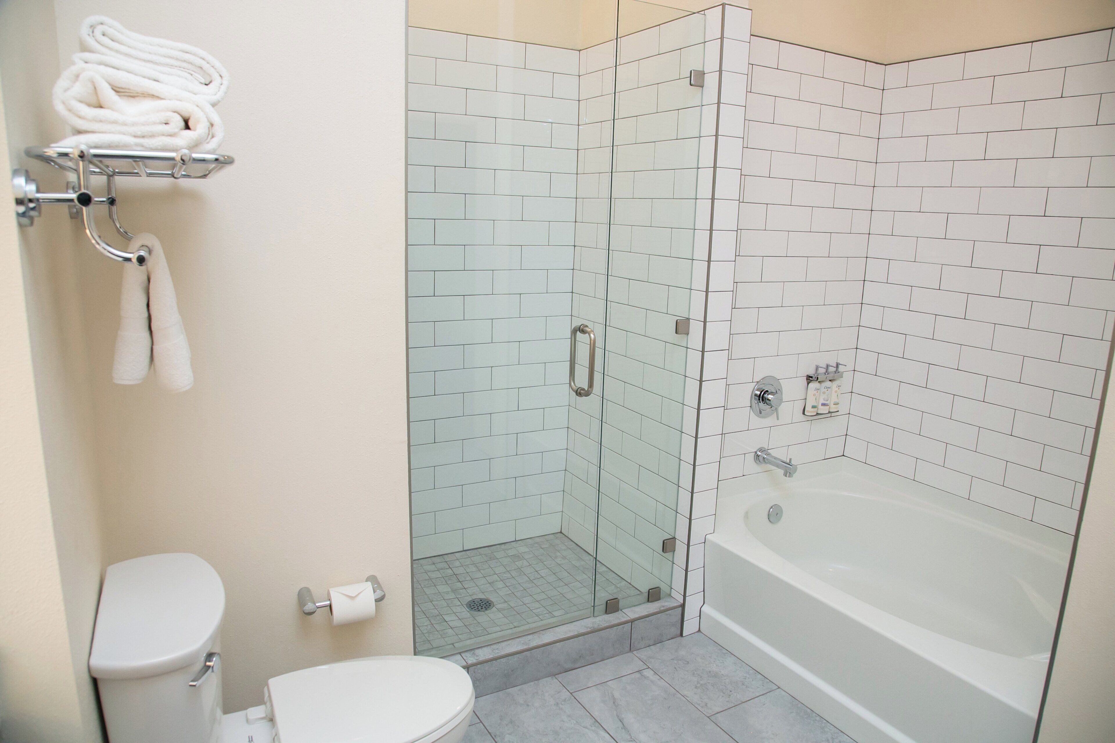 A bathroom with a glass-enclosed shower, a white bathtub, and a toilet.