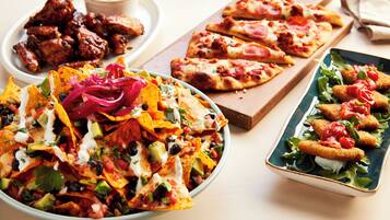 A variety of dishes including nachos, pizza, and fried items on a table.