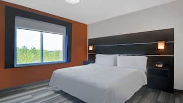 A modern hotel room with a large window, a neatly made bed, a nightstand with a phone, and a wall-mounted light fixture.