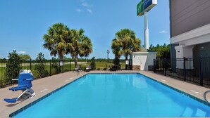 A clear blue pool with lounge chairs and a sign for Holiday Inn Express.
