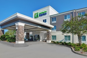 Edificio de Holiday Inn Express con entrada cubierta, pilares de piedra y cielo despejado.
