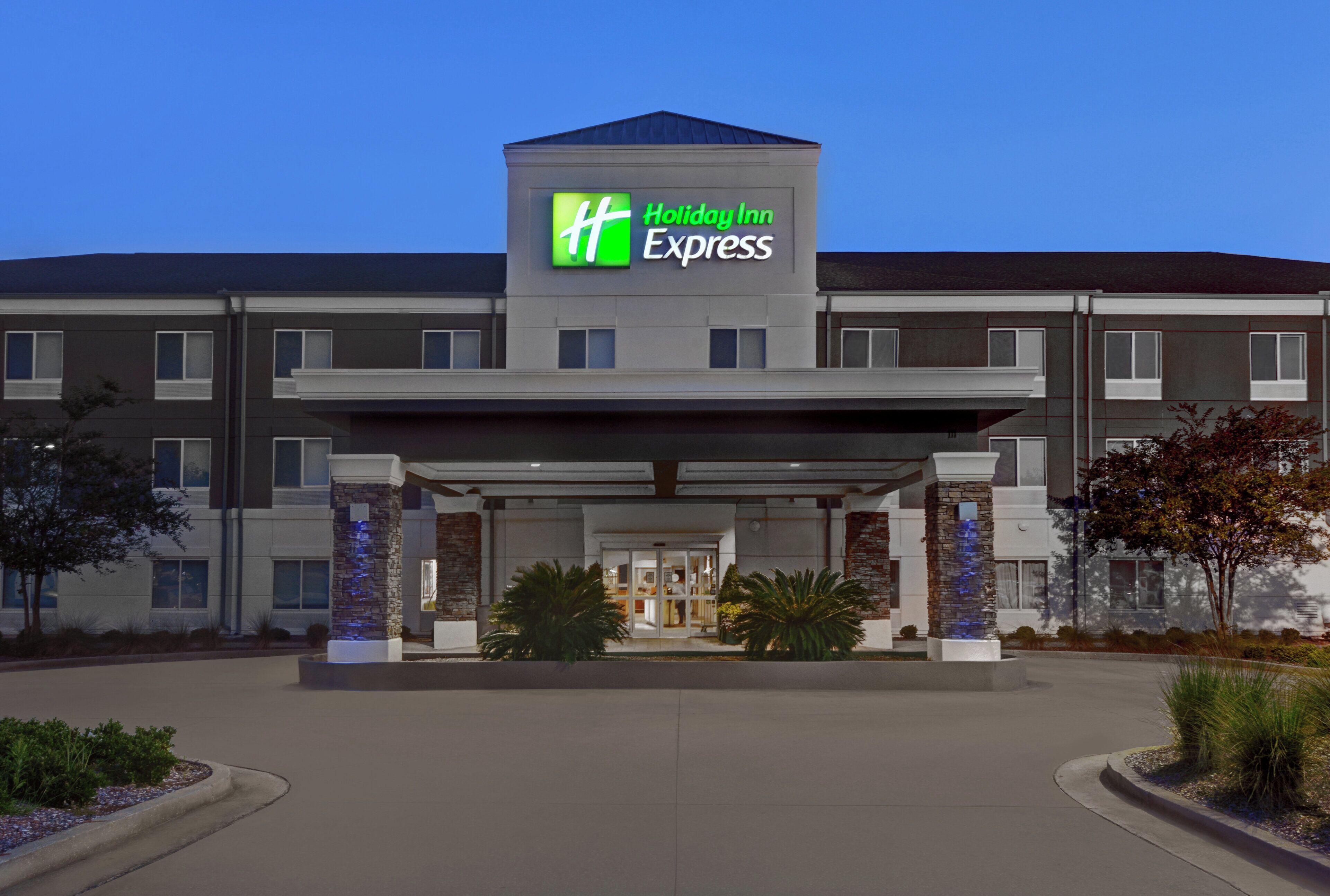 A Holiday Inn Express hotel with a modern facade, a covered entrance, and a landscaped front yard.