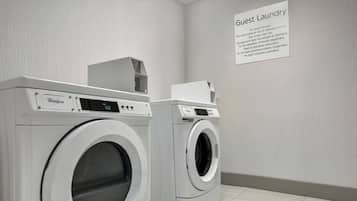 Zona de lavandería para huéspedes con dos lavadoras Whirlpool y un cartel con instrucciones para el lavado.