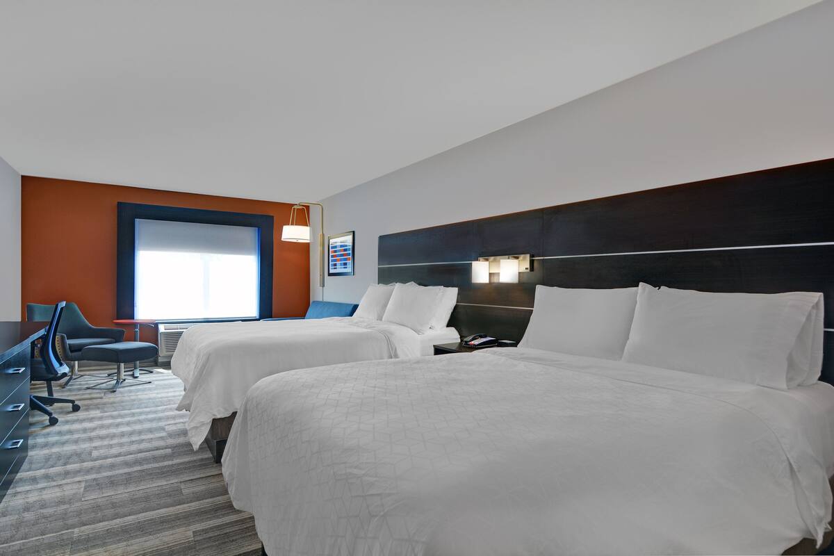 A hotel room with two beds, a desk, and a chair.