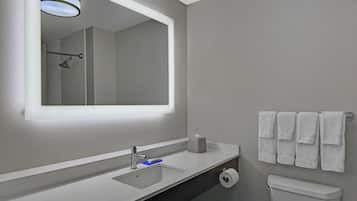 A bathroom with a large mirror, a sink, a toilet, and a towel rack.