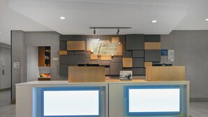 A reception desk with a digital display, a check-in counter, and a wall-mounted information board.