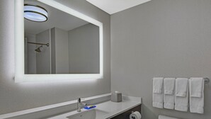 A modern bathroom with a large mirror, a sink, a toilet, and a towel rack. - Holiday Inn Express Atmore by IHG (Atmore)