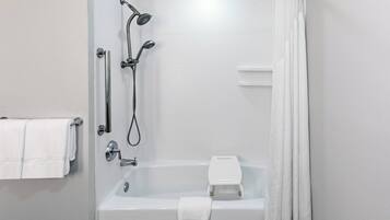 Un baño moderno con bañera, ducha y barras de apoyo.