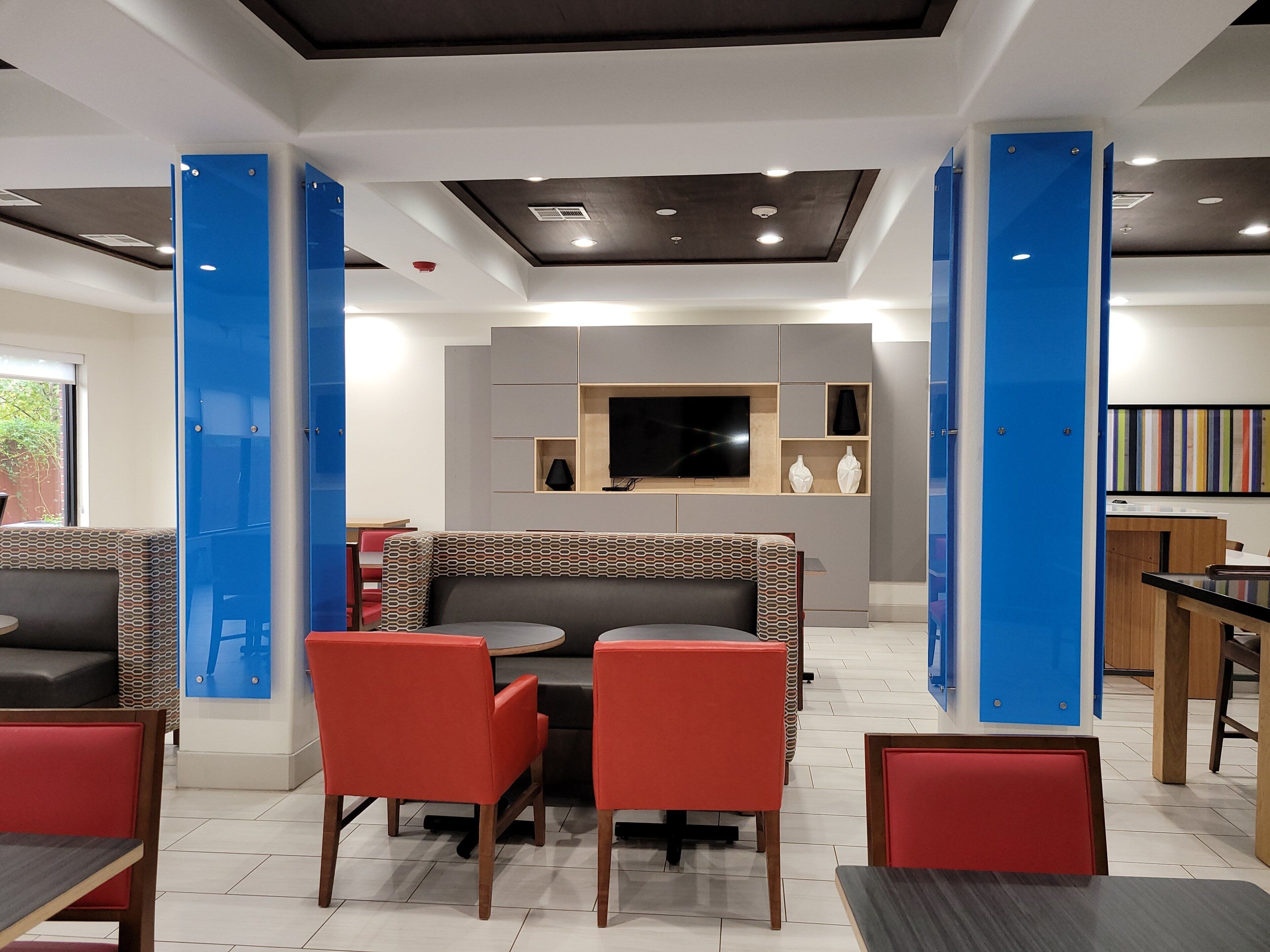 A modern interior with a central seating area, a flat-screen TV mounted on the wall, and a staircase with blue accents.