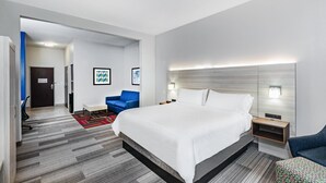 Una habitación de hotel moderna con una cama grande, un escritorio, una silla y un pequeño sofá.