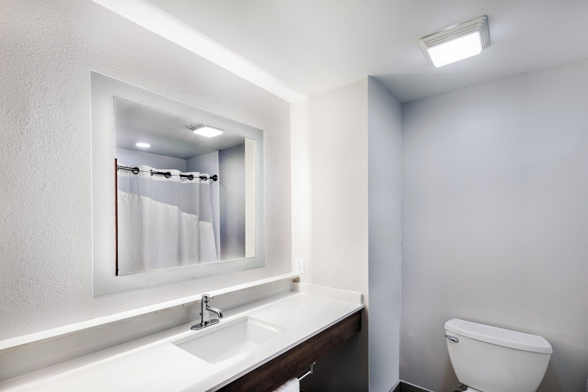 A modern bathroom with a white sink, a mirror, and a toilet.
