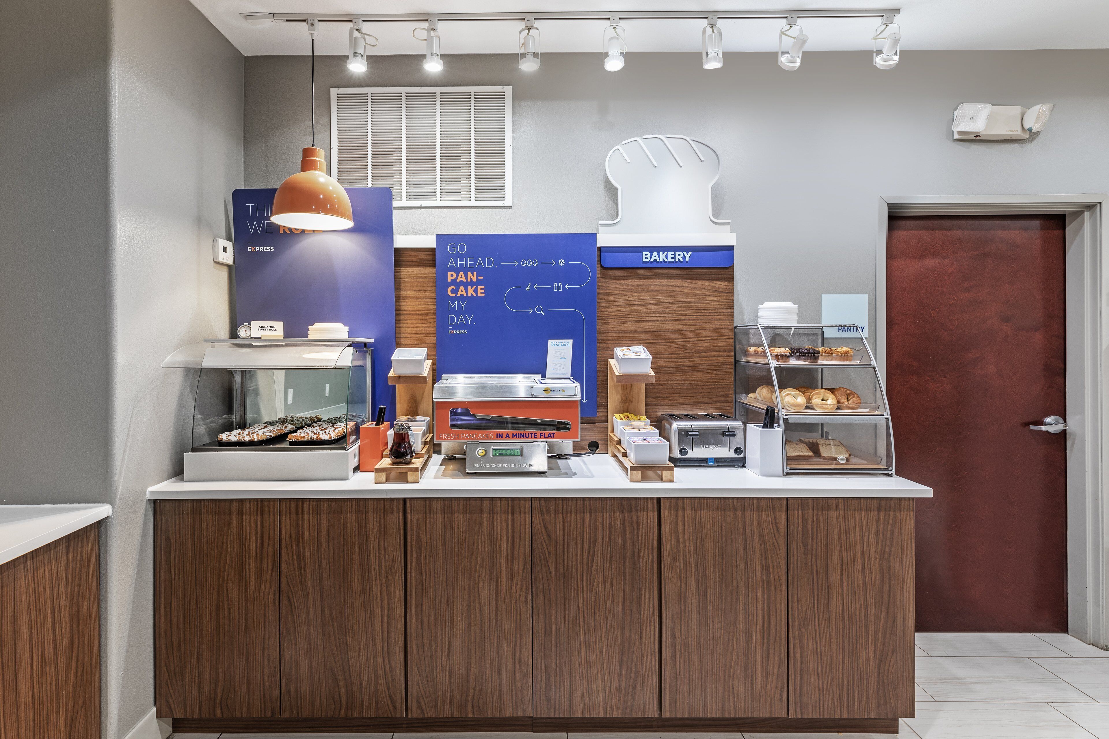 A bakery counter with a sign for fresh pancakes, a coffee machine, and a display case with pastries.