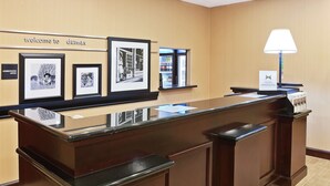 A reception desk with framed black and white photographs on the wall, a minibar, and a lamp. - Hampton Inn and Suites Dumas (Dumas)