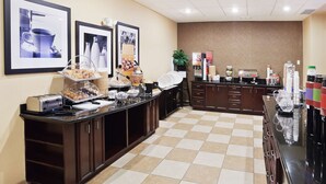 A buffet area with food stations, a coffee machine, and a plant.