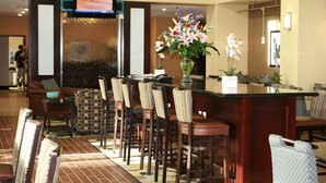 A hotel lobby with a reception desk, seating area, and a large floral arrangement. - Hampton Inn and Suites Dumas (Dumas)