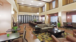 A spacious lobby with a high ceiling, a central seating area with sofas and chairs, and a dining area with tables and chairs. - Hampton Inn and Suites Dumas (Dumas)