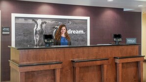 A hotel reception desk with a large framed picture of cows and the word "dream." on the wall. - Hampton Inn Richmond Airport (Sandston)