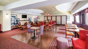 A spacious restaurant with high ceilings, wooden tables and chairs, and a red patterned carpet. - Hampton Inn Richmond Airport (Sandston)