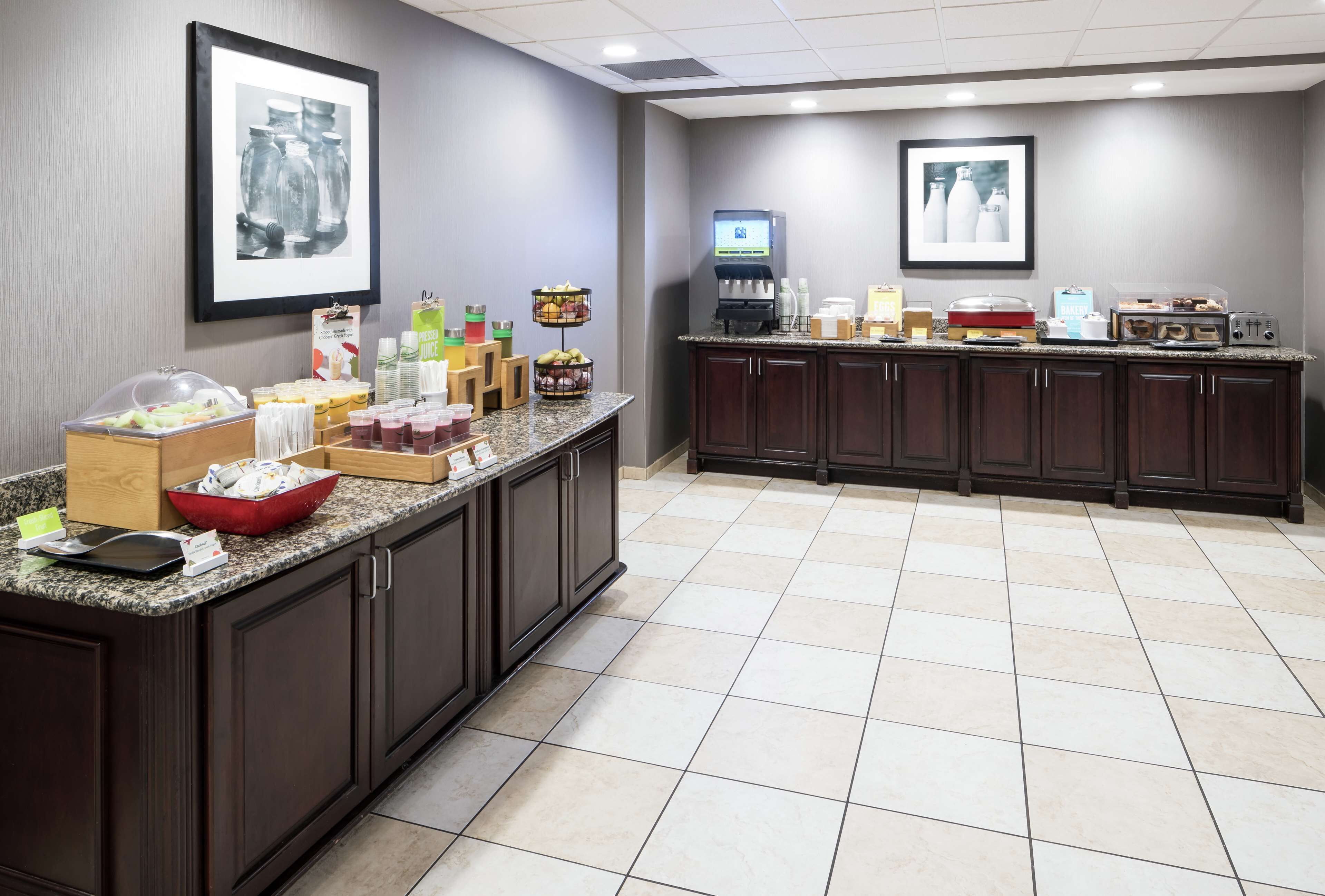 A hotel breakfast area with a buffet setup, including various food items and beverages.