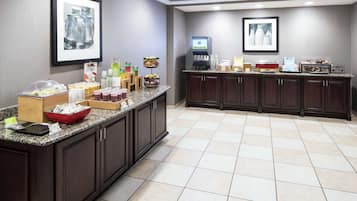 A hotel breakfast area with a buffet setup, including various food items and beverages.