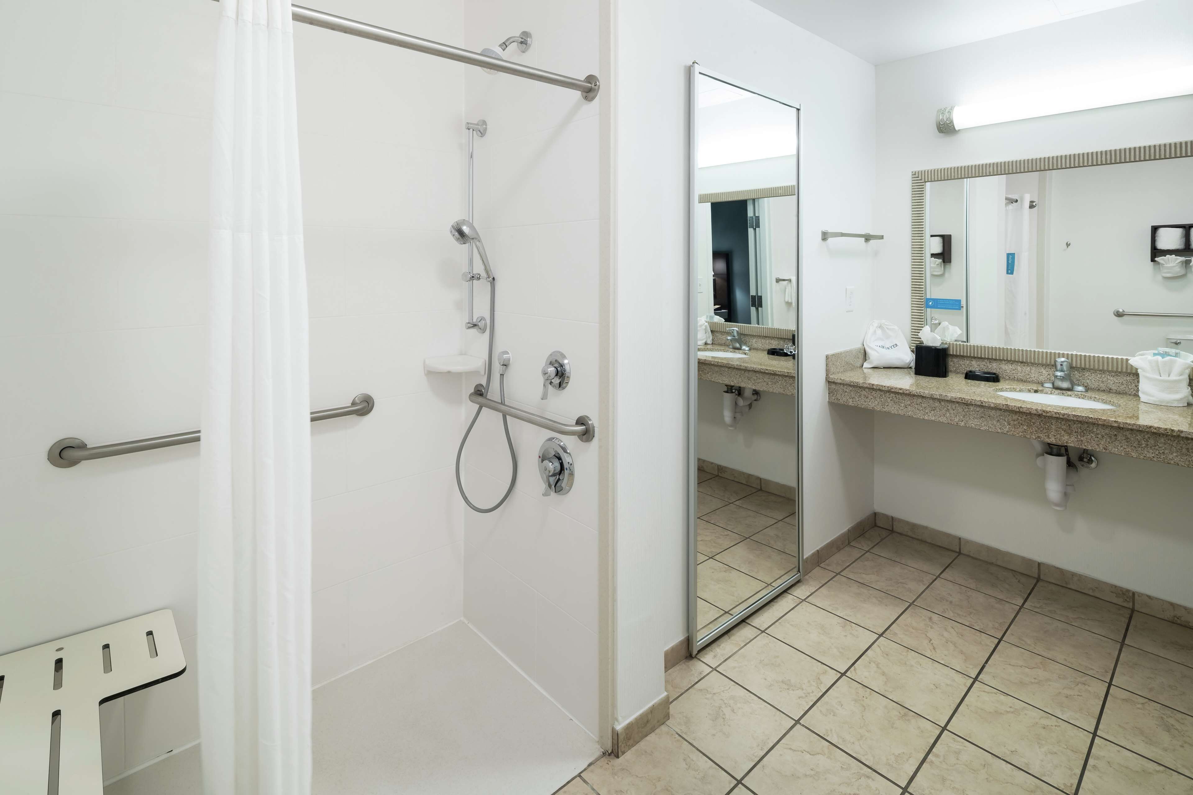Un baño moderno con cabina de ducha, un espejo grande y un lavabo con toallero.