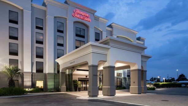 A modern hotel with a prominent neon sign, large columns, and a well-lit entrance. - Hampton Inn & Suites Panama City Beach-Pier Park Area (Panama City Beach)