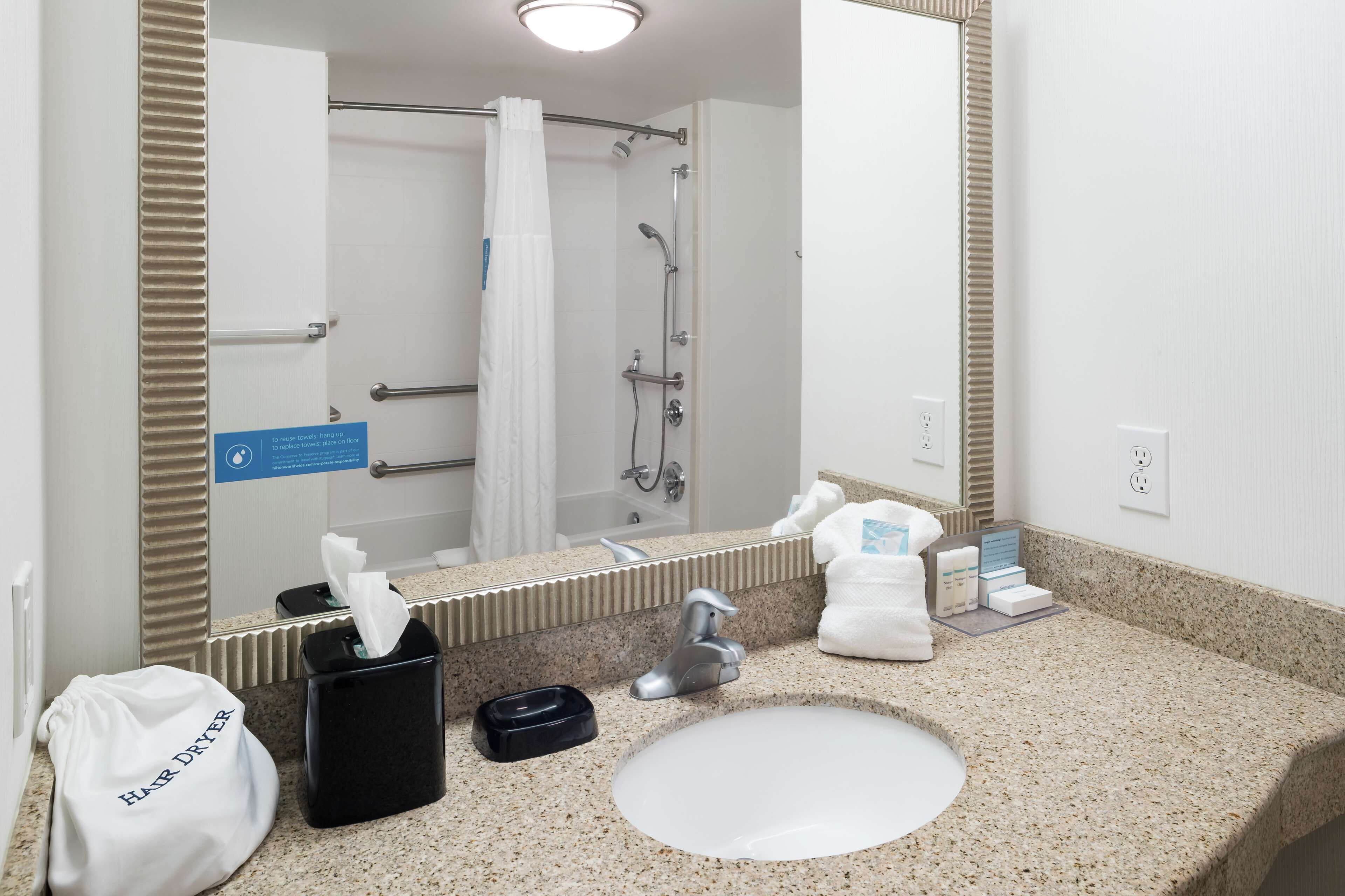 A bathroom with a sink, mirror, towel rack, and shower area.
