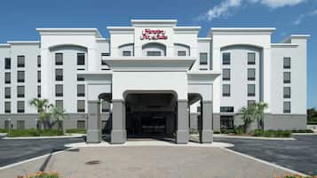 Un grand hôtel moderne, doté d’une entrée imposante et d’une enseigne indiquant « Hampton Inn & Suites ».
