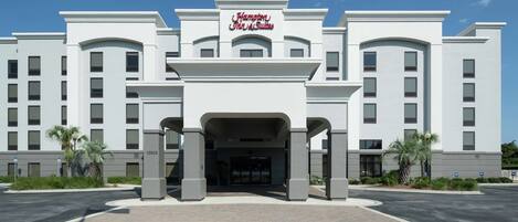 A large, modern hotel with a prominent entrance and a sign reading "Hampton Inn & Suites."