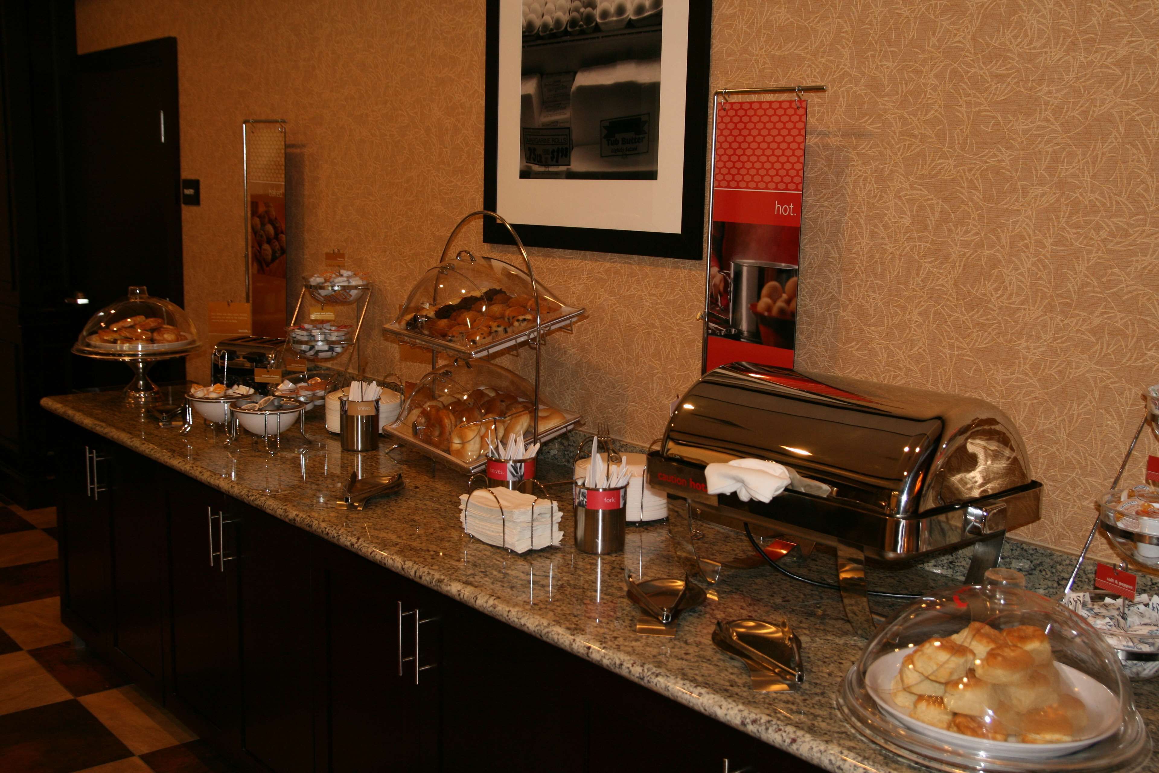 A buffet counter with various food items, including pastries and bread, and a coffee machine.