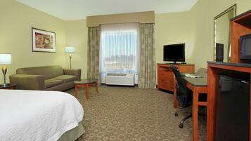 A hotel room with a bed, a desk, a chair, a television, and a window with curtains.
