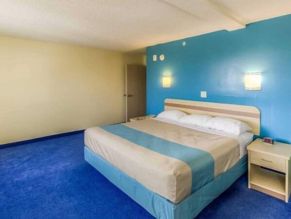 Una cama individual con cabecera, una mesita de noche y dos luces fijadas a la pared.