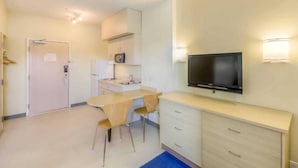 Cocina compacta con zona de comedor, televisor de pantalla plana en la pared y una puerta con un letrero.
