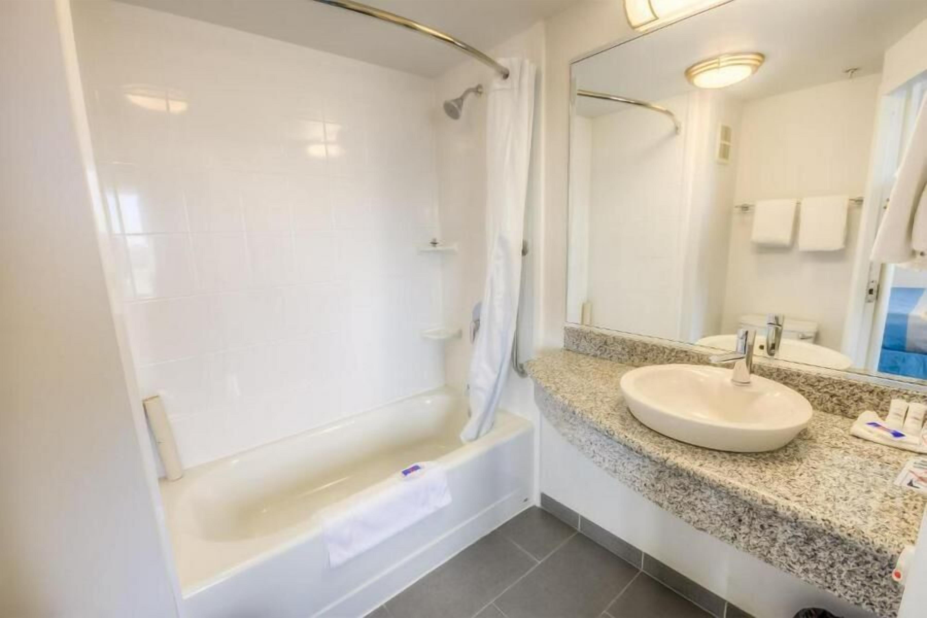 A bathroom with a bathtub, a sink, and a mirror.