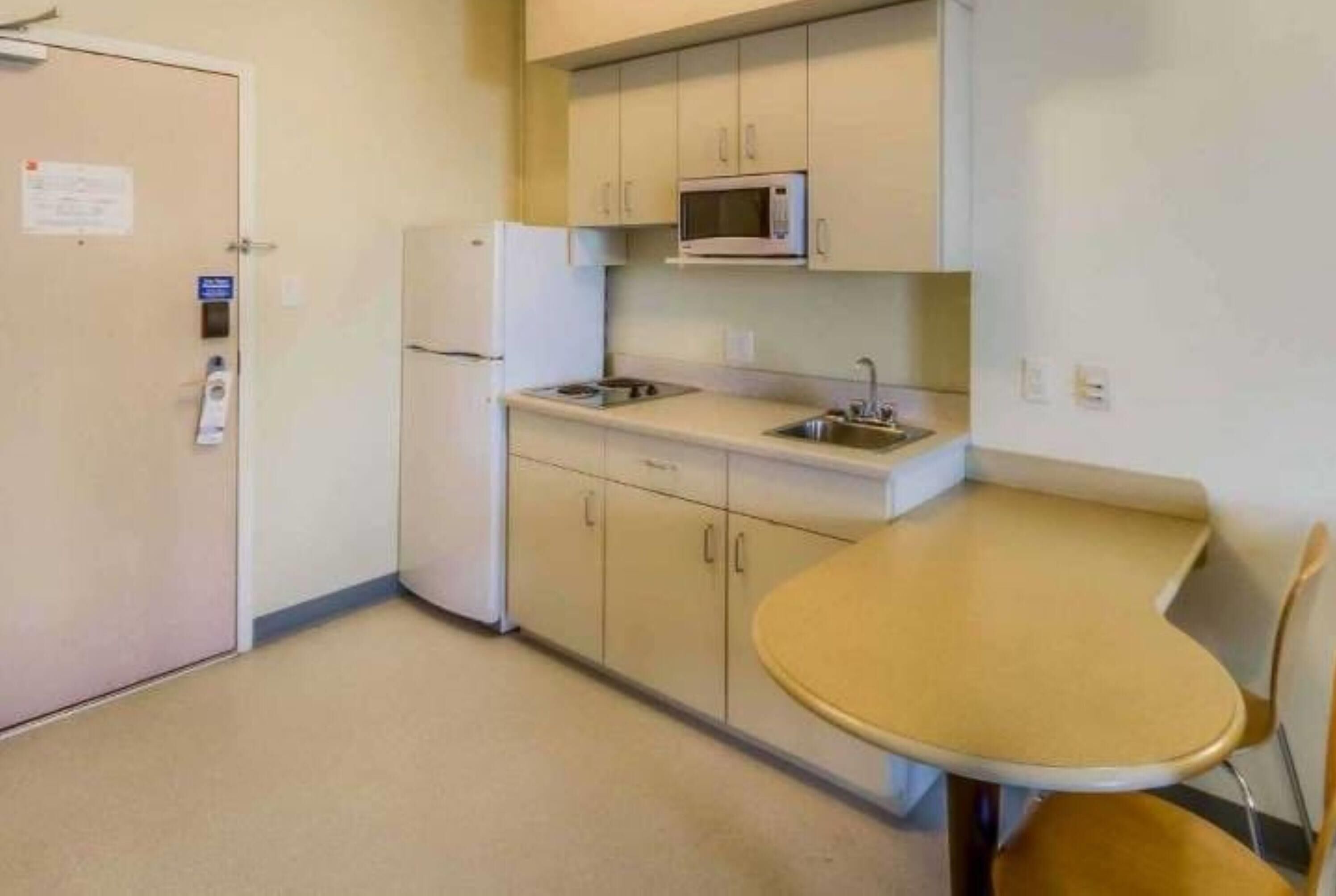 A compact kitchen with a microwave, sink, and a small dining table.
