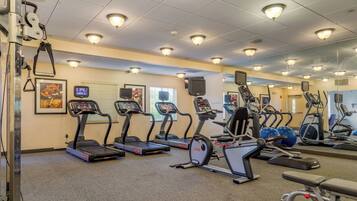 Une salle de sport équipée de tapis de course, de vélos elliptiques et de ballons d’exercice.