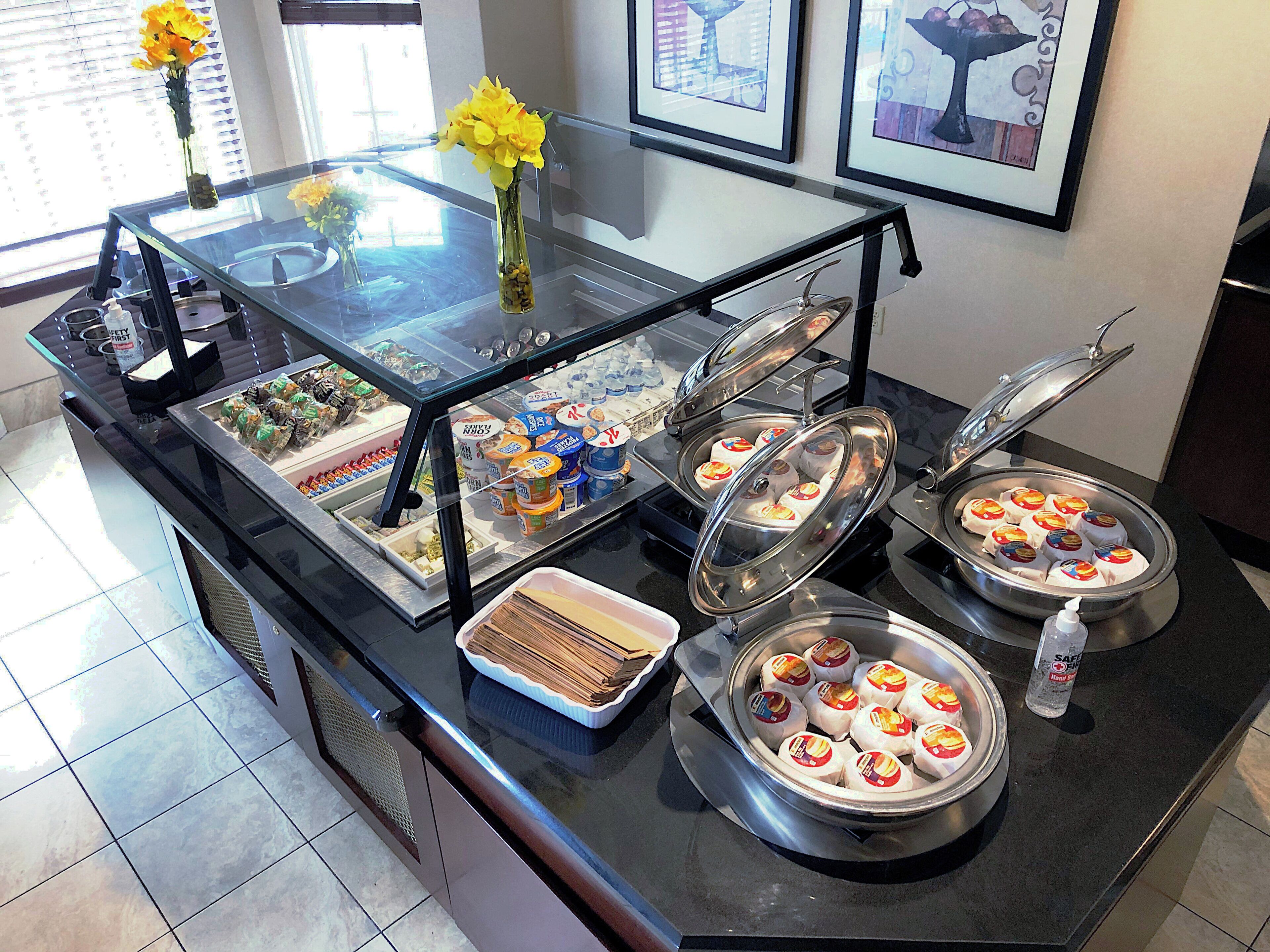 A buffet setup with various food items and a vase of yellow flowers.