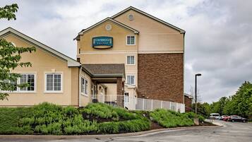Un hotel Staybridge Suites con un edificio de dos pisos, un acceso cubierto y un estacionamiento.