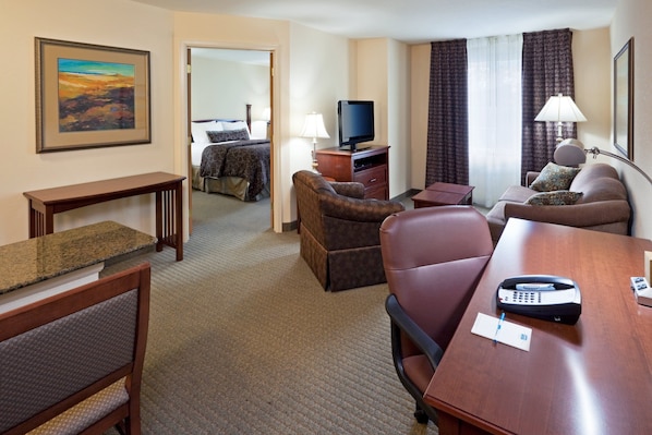 Une chambre d’hôtel équipée d’un lit, d’un bureau, d’une chaise, d’un canapé, d’une télévision et d’une lampe.