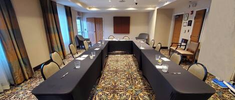 A conference room with a long table, chairs, and a patterned carpet.