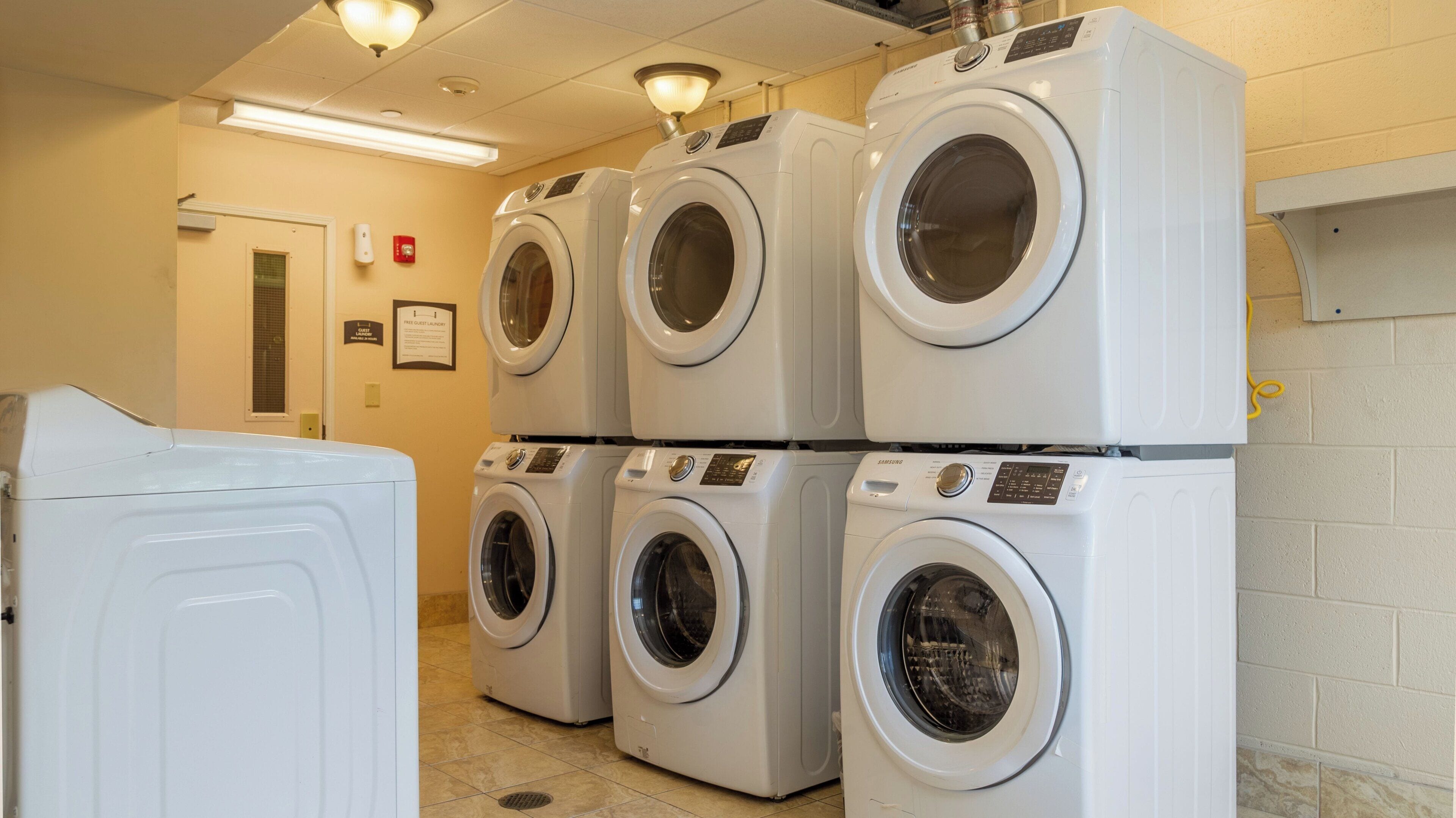 A laundry room with multiple stacked washing machines and a single dryer.
