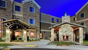 A multi-story building with stone facades, large windows, and a central courtyard with a fire feature. - Staybridge Suites Salt Lake-West Valley City by IHG (West Valley City)