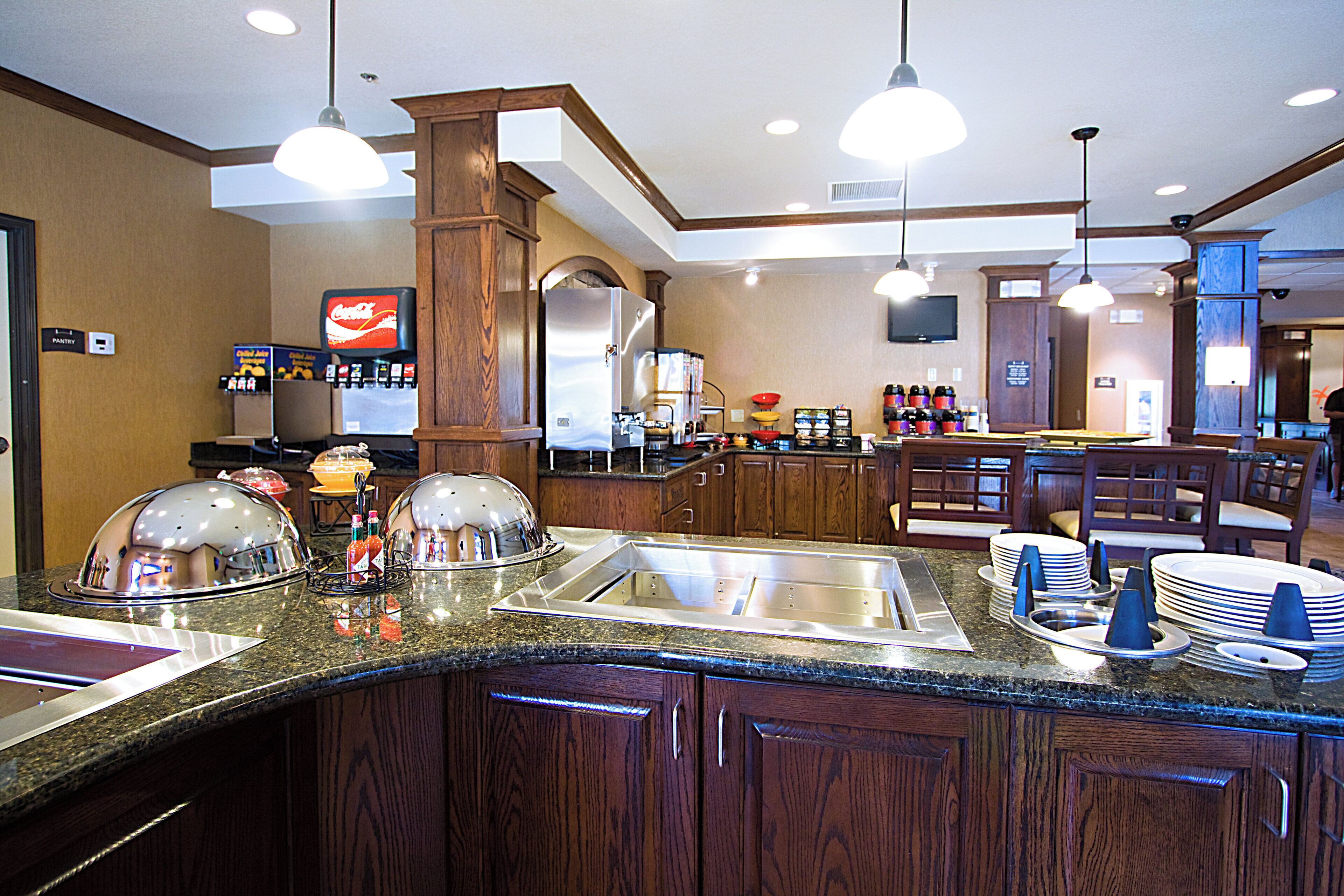 Cozinha de hotel com buffet, incluindo frigorífico, máquina de café e dispensador de Coca-Cola.
