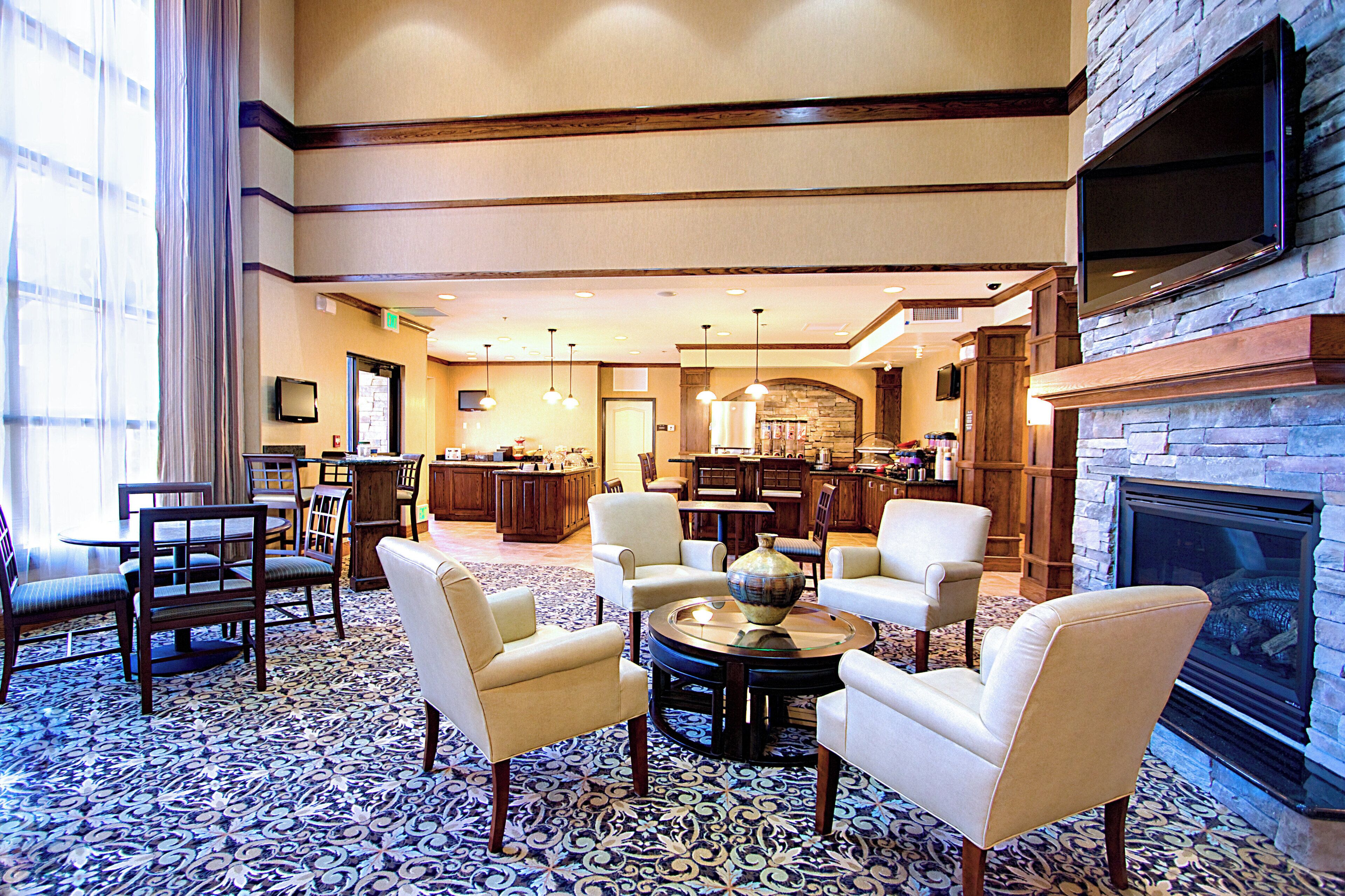 A hotel lobby with a fireplace, seating area, and a bar.