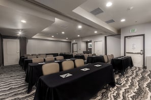 A conference room with tables, chairs, and an exit sign. - Staybridge Suites Salt Lake-West Valley City by IHG (West Valley City)