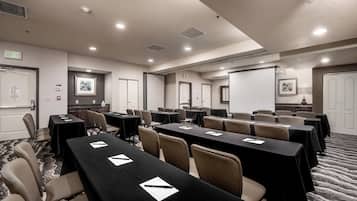 A conference room with multiple tables and chairs, equipped with nameplates and pens, and exit signs on the walls.